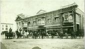 Original title:  Courtesy Saskatoon Public Library. Street view of J.F. Cairns Store, 204-222 2nd Avenue South (near corner of 21st Street), next to corner he sold to Bank of Commerce. Lined up in street are nattily dressed men with horses and buggies. [before July 1912]
Creator/Photographer:	McKenzie, Peter.